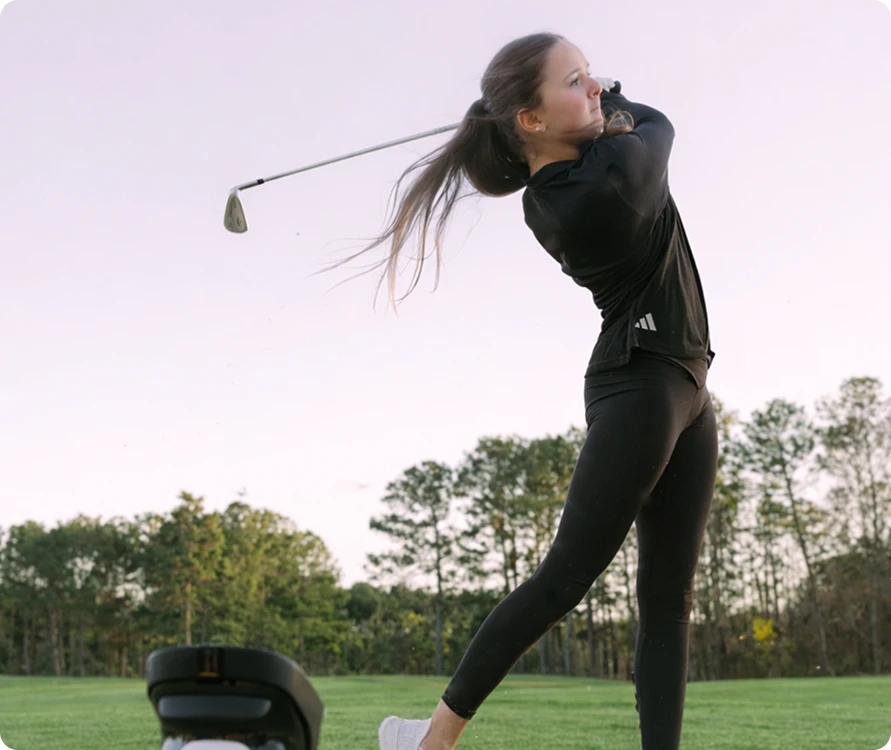 Young girl swinging golf club near Uneekor EYE MINI Launch Monitor